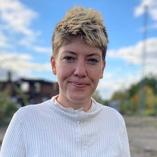 Billedet af oversætter og forfatter Ditte Hermansen er taget udenfor med skyer og himmel i baggrunden.