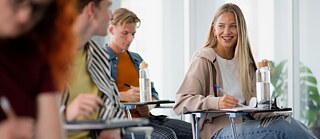 In a classroom, a student enjoys a moment with her friends, all focused on their conversation and the learning environment