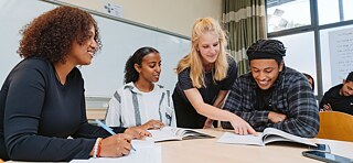 Blick von oben auf junge Leute mit aufgeschlagene Notizbücher.