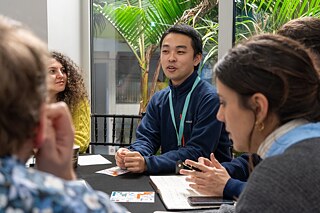 A group of people are sitting around a table having a lively conversation.