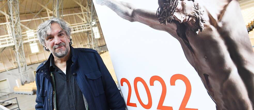 Director Christian Stückl, who has modernized the play a lot since 1990, stands next to the poster advertising the 2022 Passion Play, which had been postponed for two years because of the coronavirus pandemic.