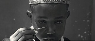 Ein Junge, der einen Gegenstand auf sein Gesicht richtet