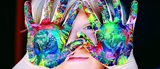 Дитина тримає перед обличчям розмальовані яскравими фарбами руки. &copy; Фото: Alexander Grey / pexels.com Долоні у яскравих фарбах