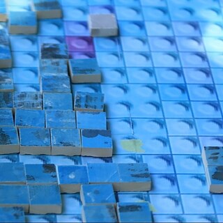 Kinderhände arbeiten an einer blau-bunten Mosaik