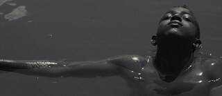 Ein Junge, der mit geschlossenen Augen in ein Gewässer blickt