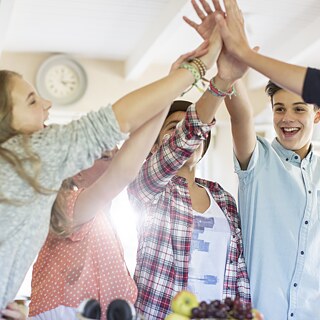Students clap their hands against each other in the classroom.