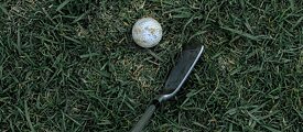 Golfschläger und -ball im Gras