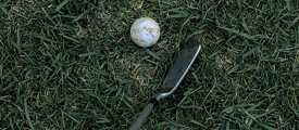Crosă de golf și minge de golf în iarbă
