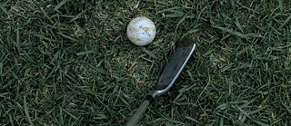 Golfschläger und -ball im Gras