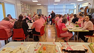 Eine Gruppe in pinkfarbenen T-Shirts isst Kuchen.