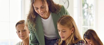 Lehrerin unterstützt Schüler*innen im Unterricht in Gruppen