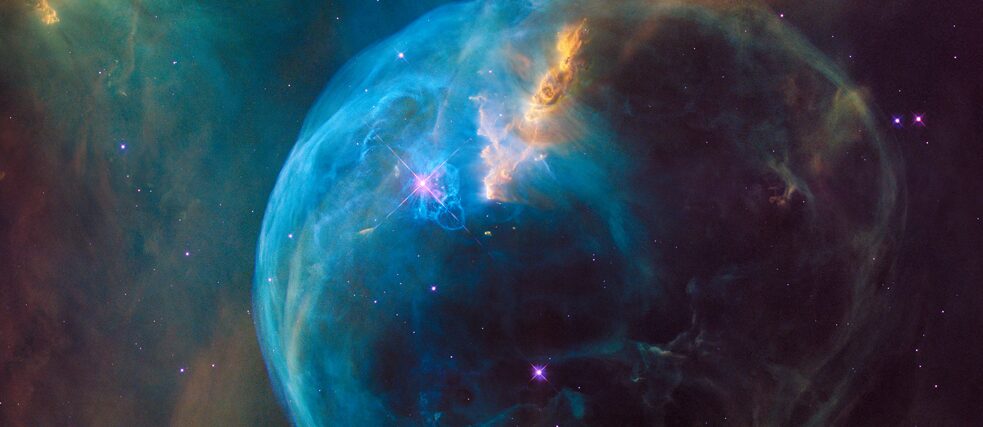 A vibrant image of the Bubble Nebula, showcasing a glowing blue sphere of gas and dust surrounded by swirling clouds of orange and green, with stars scattered throughout the dark cosmic background.