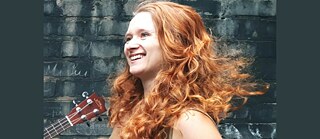 Rothaarige lachende Frau Irene Hoffmann mit Ausschnitt einer Gitarre