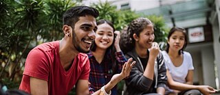 Four people sit on a fine bench and laugh
