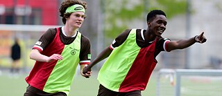 Fußballspieler fassen sich an den Händen und zeigen in eine Richtung