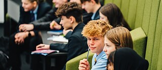 Junge hat Bleistift in der Hand und schaut in die Kamera