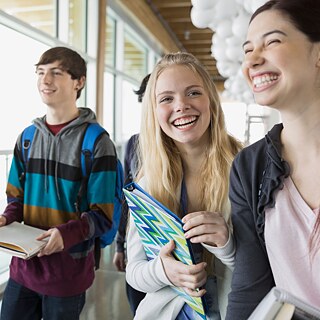 Drei lachende Schüler*innen in einer Schule