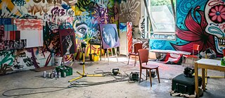 A colourful art room, with paintings and graffiti
