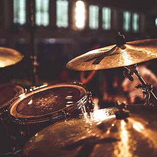 Nahaufnahme eines Schlagzeugs auf einer Bühne, beleuchtet von warmem Licht