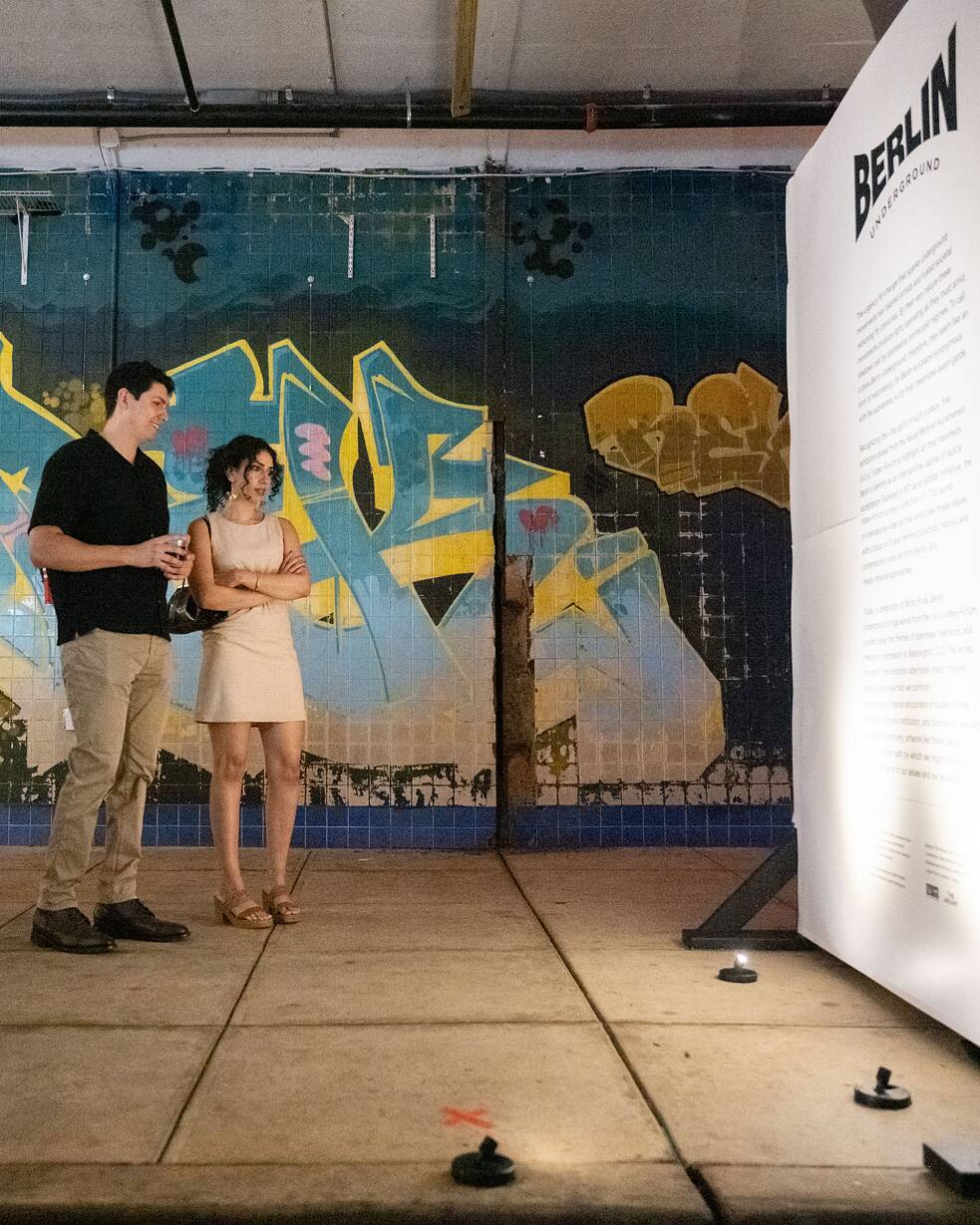Two people looking at a work of art as part of the Berlin Underground exhibition in Washington, DC