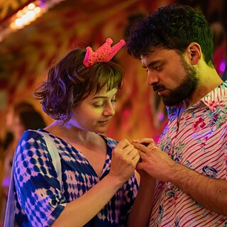 A young woman and a man hold hands.