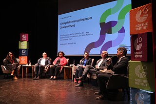 Sechs Personen sitzen auf der Bühne und diskutieren