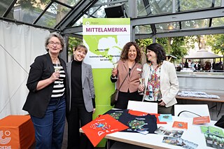 Four women stand at the information table of the South America region and laugh