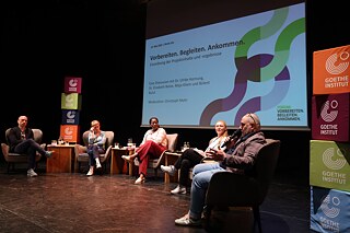 Fünf Personen sitzen auf der Bühne und diskutieren