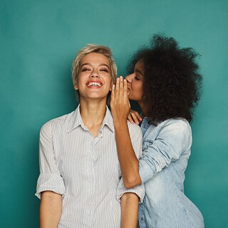 Der Moderator eines Radiosenders sitzt mit Kopfhörern vor dem Laptop und spricht lachend ins Mikrofon.