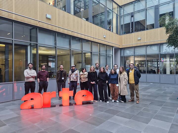 Auf dem Foto sieht man einige Teilnehmende vor einem lebensgroßen roten ARTE-Schriftzug