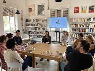 In der Bibliothek des Kultur Ensemble Palermo sitzen Teilnehmende um einen Tisch herum und diskutieren