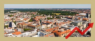 Die Stadt Leipzig von oben. Man sieht viele Häuser, im Hintergrund einen großen Park. 