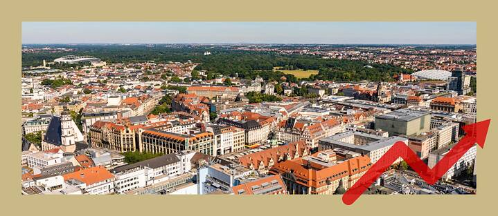 Die Stadt Leipzig von oben. Man sieht viele Häuser, im Hintergrund einen großen Park. 