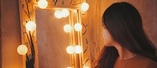 Ein Mädchen schaut in einen Spiegel.