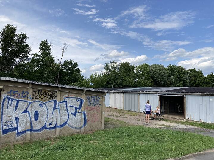 Zwei Kinder spielen in der Ferne Schach vor einer Reihe Garagen im Harthweg