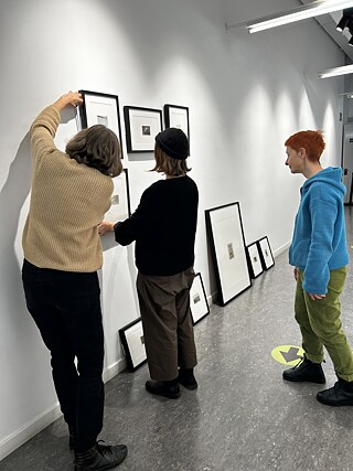Mehrere Personen hängen Bilder an die Wand