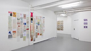 Eine weiße Wand, auf der verschiedene Papiere für die Ausstellung ausgestellt sind.