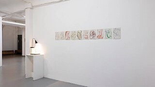 Eine weiße Wand mit einer Reihe von Gemälden, die verschiedene künstlerische Ausdrucksformen und Stile zeigen.