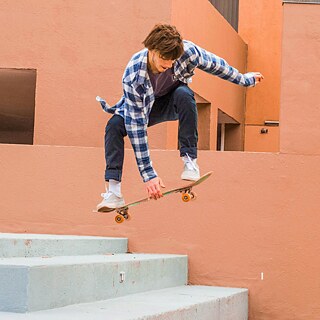 Ein Skateboarder springt über eine Treppe.