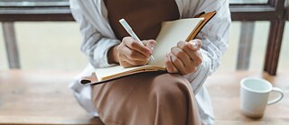 Person writes in a book