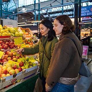  Zwei Frauen sehen sich Obst und Gemüse an einem Marktstand an