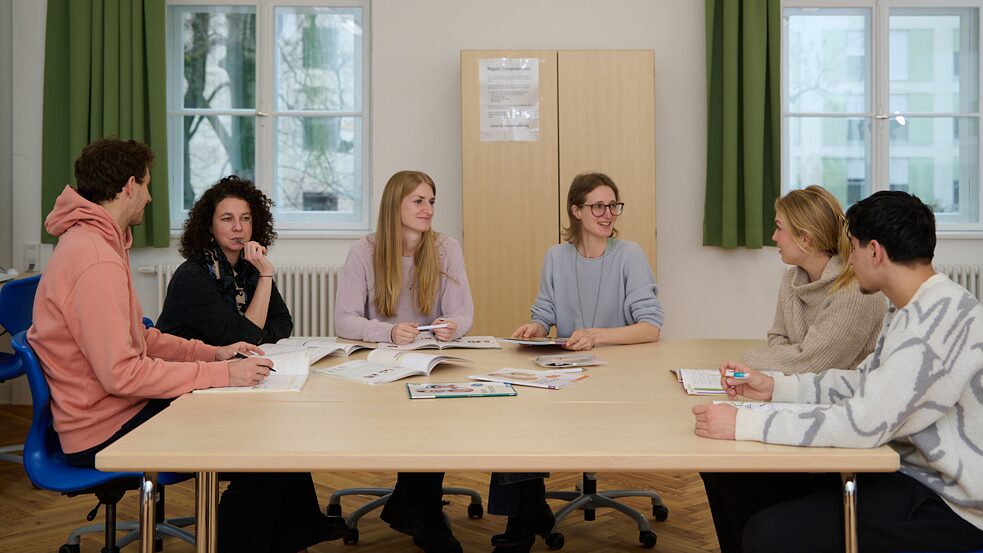 Eine Gruppe von Frauen sitzt an einem Tisch mit aufgeschlagenen Lehrbüchern.