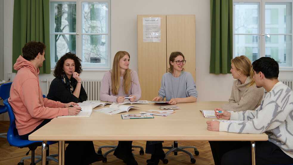 Eine Gruppe von Frauen sitzt an einem Tisch mit aufgeschlagenen Lehrbüchern.