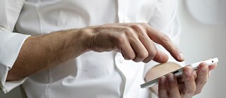 Close-up of a person using a smartphone with both hands. © © Unsplash Getting Connected in Germany: Internet, Phones & Data Privacy