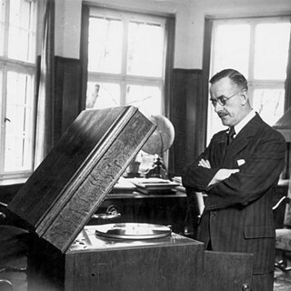 München.- Thomas Mann in seiner Wohnung vor einem Grammophon / Schallplattenspieler