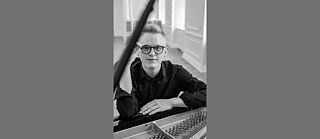 Jan Čmejla assis au piano (photo en noir et blanc)