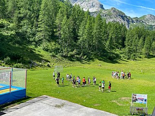 Jugendliche spielen auf einer Wiese in den Bergen.