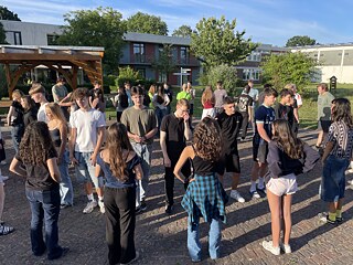 Jugendliche stehen auf einem Hof im Kreis.