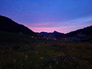 Sonnenuntergang in den Bergen, im Vordergrund eine blühende Wiese.