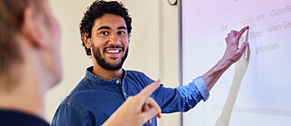 Ein fröhlicher Mann deutet mit Gesten auf ein Whiteboard und teilt mit einem Lächeln seine Ideen mit